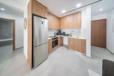 a kitchen with wooden cabinets and a stainless steel refrigerator at Serene Gardens 2BR w Pool in Livadhia