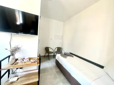 a bedroom with a bed and a desk with a television at Golden Sun Rooms - Adults Only in Ayia Napa