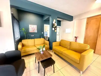 a living room with two yellow couches and a table at Golden Sun Rooms - Adults Only in Ayia Napa