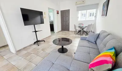 a living room with a couch and a flat screen tv at Citycenter Comfy Apartment in Larnaka