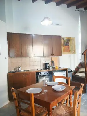 a kitchen with a wooden table with chairs and a stove at Traditional Cozy Retreat in Skarinou