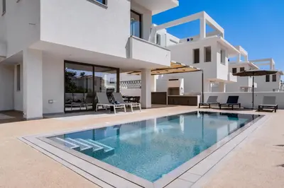 a villa with a swimming pool in front of a house at St Nicholas Luxury 3-Bed Villa in Paralimni