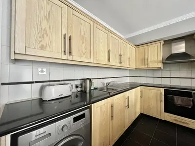 a kitchen with wooden cabinets and a washing machine at STAY Napa Oniro Apartment in Ayia Napa