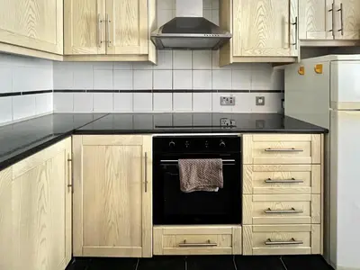 a kitchen with wooden cabinets and a black oven at STAY Napa Oniro Apartment in Ayia Napa