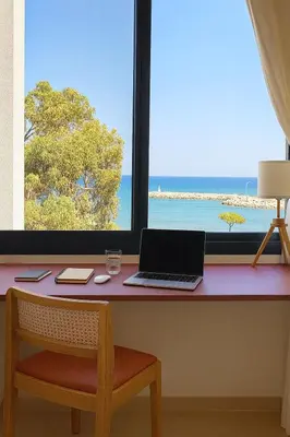 a desk with a laptop and a view of the beach at Larnaca Seaview Apartment with pool & parking in Larnaka