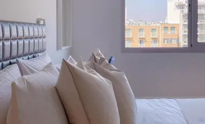 a bedroom with white pillows on a bed with a window at Plateia Suite Brillante in Nicosia