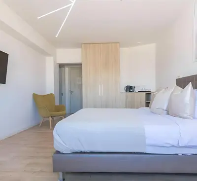 a bedroom with a large white bed and a chair at Plateia Suite Brillante in Nicosia