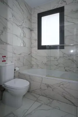 a bathroom with a toilet and a tub and a window at Luxury Modern Larnaca Central in Larnaka