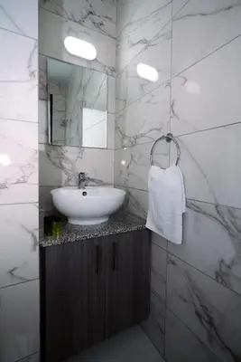 a white bathroom with a sink and a mirror at Luxury Modern Larnaca Central in Larnaka