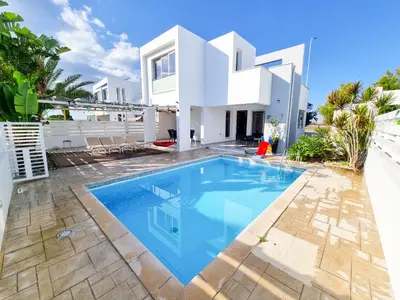 a villa with a swimming pool in front of a house at Poser Beach Villa With Private Pool And BBQ in Pervolia