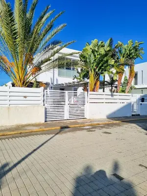 a fence with palm trees in front of a building at Poser Beach Villa With Private Pool And BBQ in Pervolia