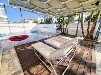 a porch with two chairs and a swing at Poser Beach Villa With Private Pool And BBQ in Pervolia