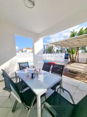 a white table and chairs on a patio at Poser Beach Villa With Private Pool And BBQ in Pervolia