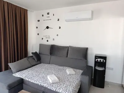 a living room with a couch and a clock on the wall at Deja Blue Apartments, North Cyprus