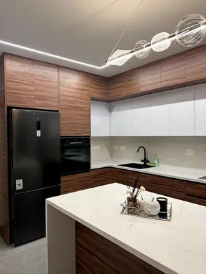 a kitchen with a black refrigerator and wooden cabinets at Mall View Modern PentHouse in Larnaka