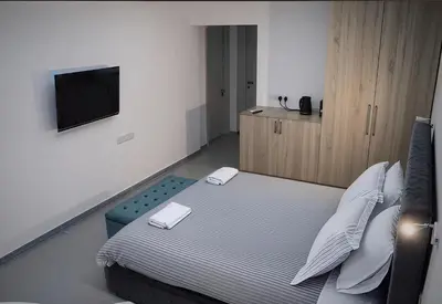 a bedroom with a bed with a tv on the wall at Plateia Suite Deluxe in Nicosia