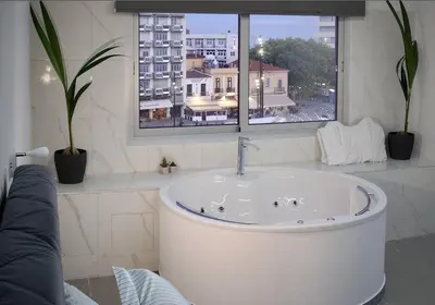 a bath tub in a bathroom with a window at Plateia Suite Deluxe in Nicosia