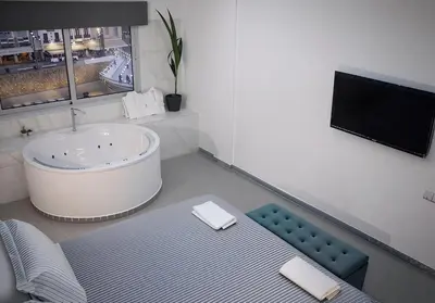 a bathroom with a tub and a tv in it at Plateia Suite Deluxe in Nicosia