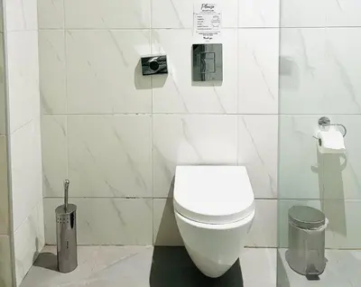 a white bathroom with a toilet and a trash can at Plateia Suite Deluxe in Nicosia