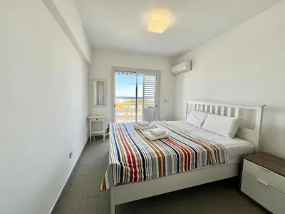 a white bedroom with a bed and a window at STAY Almyra House in Protaras