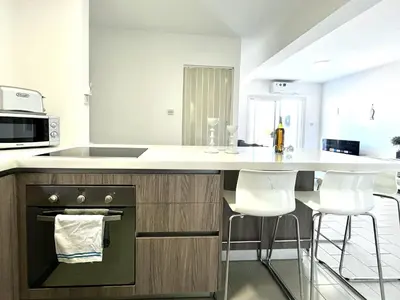 a kitchen with a stove and a counter with stools at STAY Almyra House in Protaras