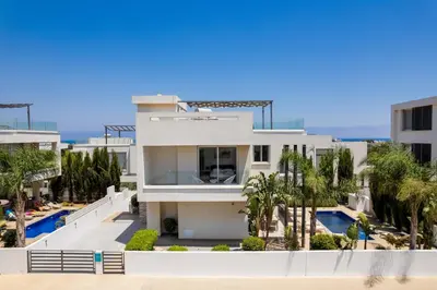 a white house with a swimming pool and palm trees at Levanda Hills Haven in Protaras in Paralimni