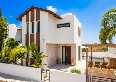 a white house with a fence and palm trees at Levanda Dreams 8 in Paralimni