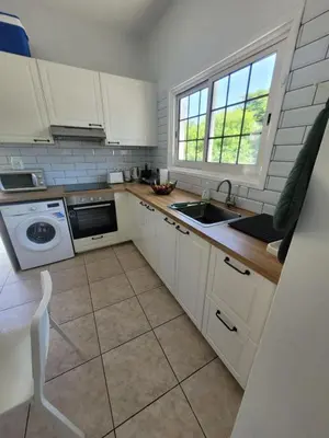 a kitchen with white cabinets and a sink at Ayia Napa Marina Luxury Villas - Aquamarine in Ayia Napa