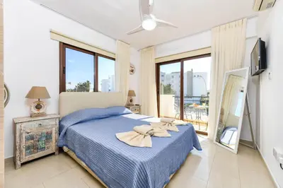 a bedroom with a blue bed and a balcony at Nissi Apartment #102 in Ayia Napa