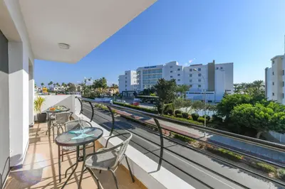 a balcony with tables and chairs and a view of a city at Nissi Apartment #102 in Ayia Napa