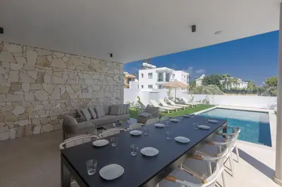 a dining room with a table and chairs and a pool at Ayia Napa Orea Villa OR9 in Ayia Napa