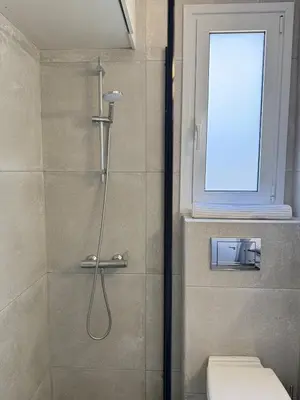 a bathroom with a shower with a toilet and a window at The Minimal Nest in Nicosia