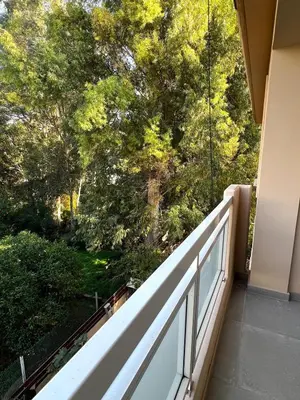 a balcony with a white railing and trees at The Minimal Nest in Nicosia