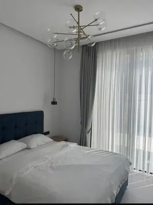 a bedroom with a bed with a chandelier and a window at Mykonos Homes Villa in Aglantzia