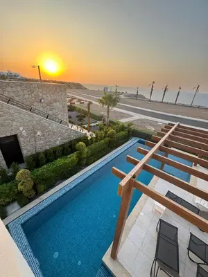 a swimming pool next to a beach with a sunset at Mykonos Homes Villa in Aglantzia