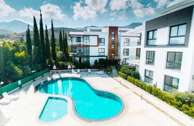 an apartment building with a swimming pool in front of a building at Eden Garden 2 bedroom Alsancak in Nicosia International Airport
