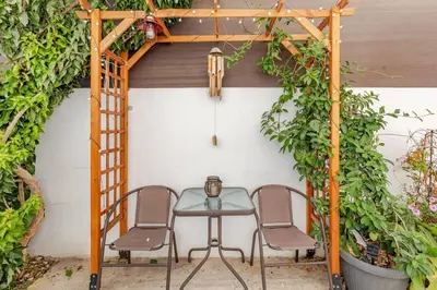 a table and chairs under a pergola with plants at Сozy and traditional - EC Studios in Larnaka