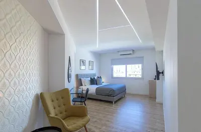 a bedroom with a bed and a chair at Plateia suite Grigio in Nicosia