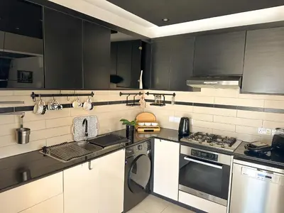 a kitchen with black and white cabinets and a dishwasher at Modern Penthouse Overlooking Pool in Pyla