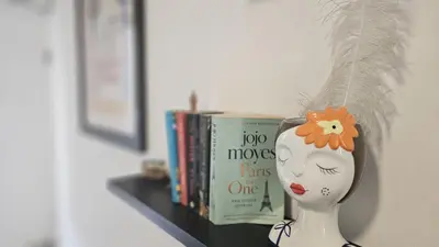 a statue of a woman with a feather on her head next to books at STAY ZEA Studio in Ayia Napa