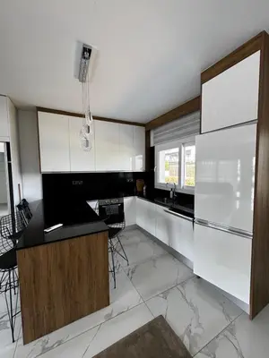a kitchen with white cabinets and a black counter top at Apartman Severny Cyprus in Iskele