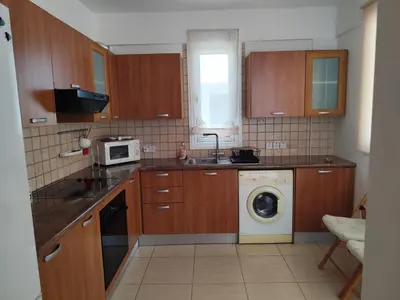 a kitchen with wooden cabinets and a washing machine at Julia Holiday Apartment in Larnaka
