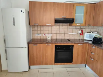a kitchen with wooden cabinets and a white refrigerator at Julia Holiday Apartment in Larnaka