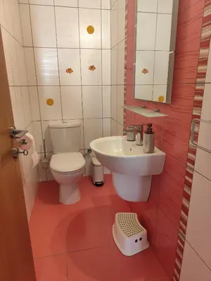 a bathroom with a white toilet and a sink at Julia Holiday Apartment in Larnaka