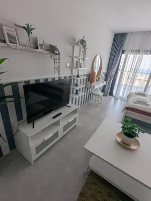 a living room with a flat screen tv on a cabinet at Caesar Blue Studio Sea View Apartment in Boğaz