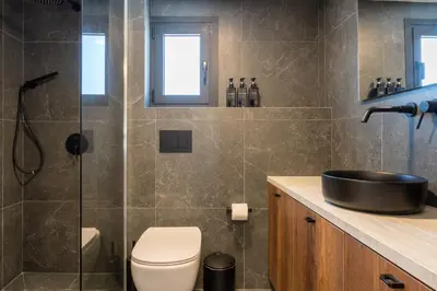 a bathroom with a toilet and a glass shower at Exquisite 2BR modern village house w private pool in Ayios Tykhonas