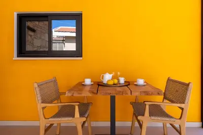 a table with two chairs and a yellow wall at Exquisite 2BR modern village house w private pool in Ayios Tykhonas