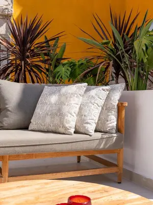 a couch with three pillows on it in front of plants at Exquisite 2BR modern village house w private pool in Ayios Tykhonas