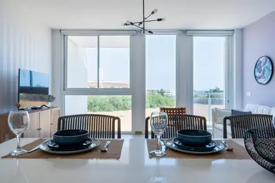 a dining room with a table with plates and wine glasses at Blu Horizon - Stylish Living with Pool & Balconies in Protaras in Paralimni