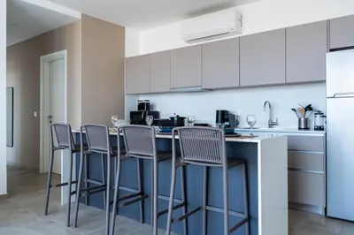 a kitchen with white cabinets and bar stools at Blu Horizon - Stylish Living with Pool & Balconies in Protaras in Paralimni